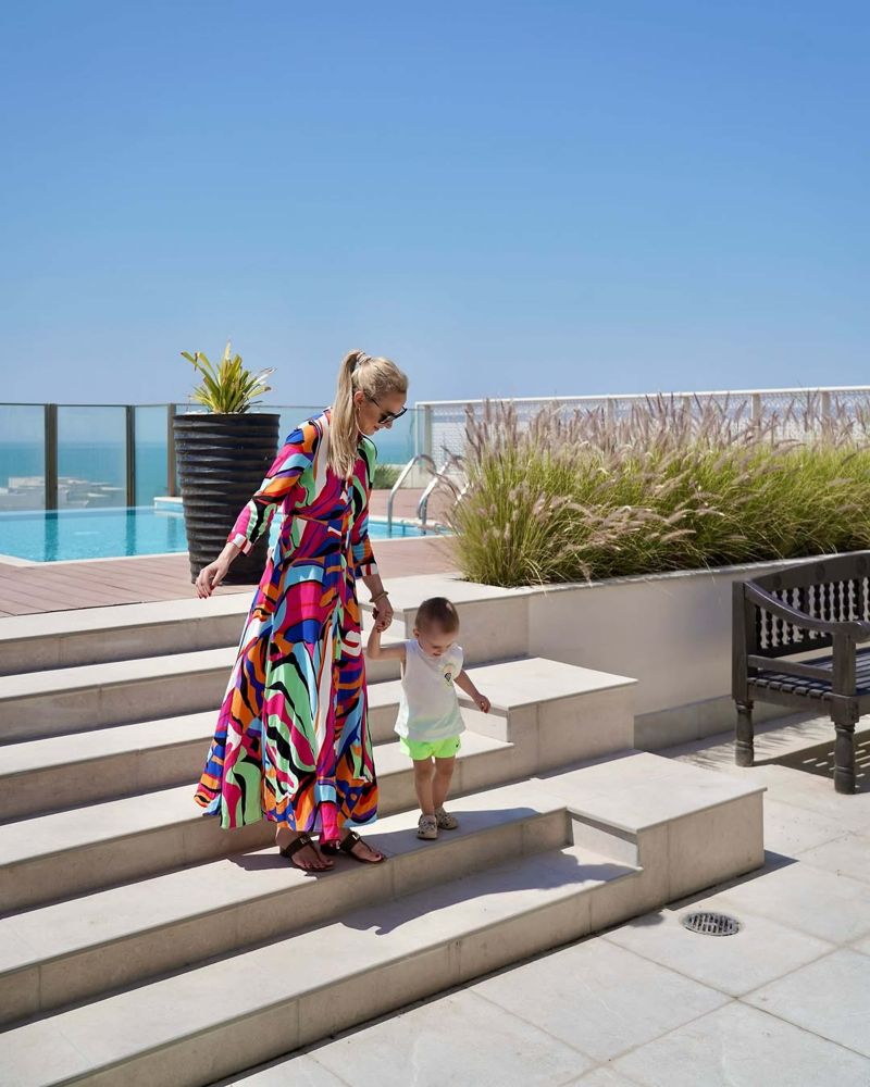 Woman holding her young son's hand at Sofitel Bahrain Zallaq Resort, enjoying a family-friendly beachside moment