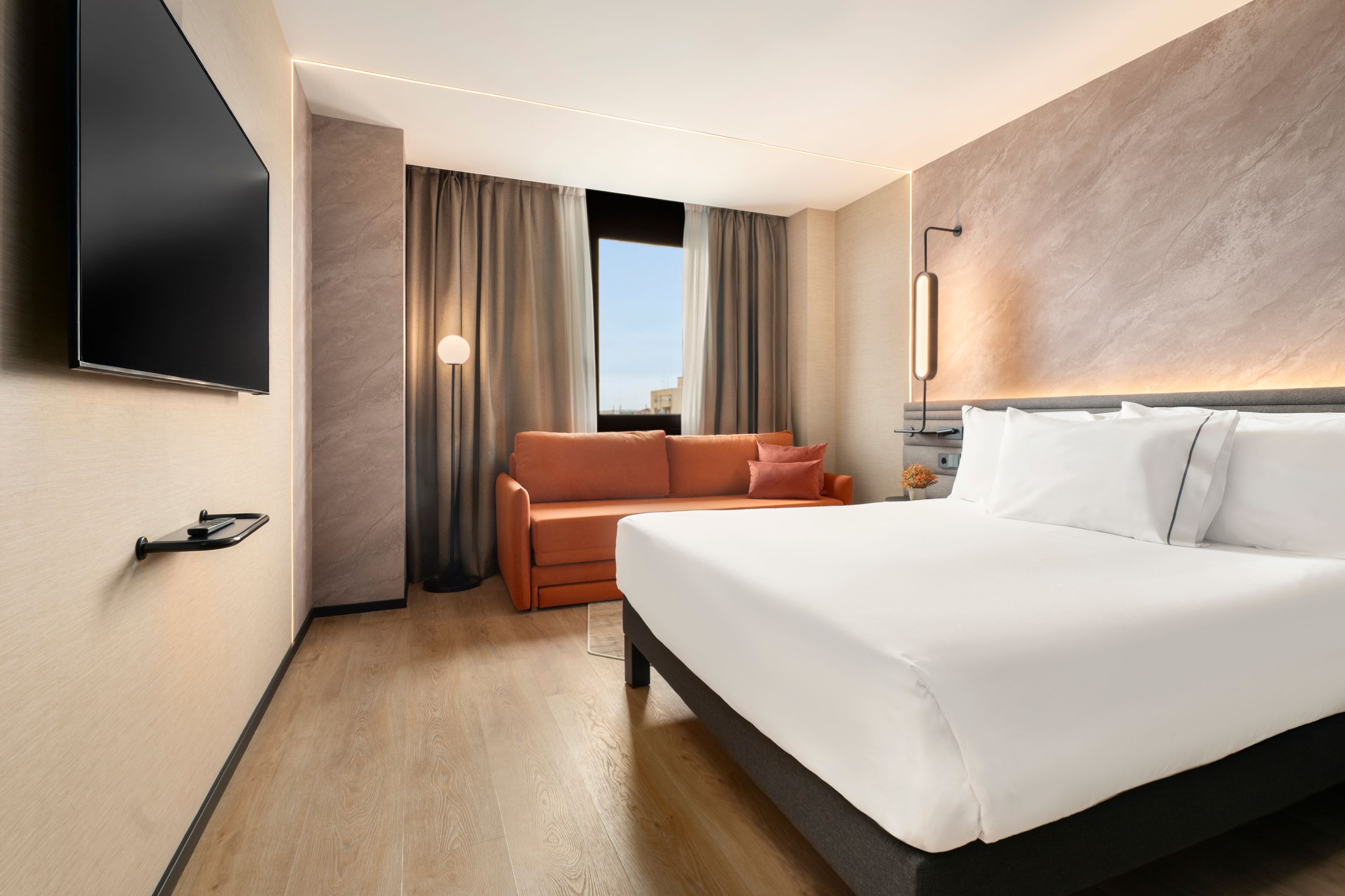 Chambre d’hôtel 4 étoiles avec grand lit et banquette près de la fenêtre 