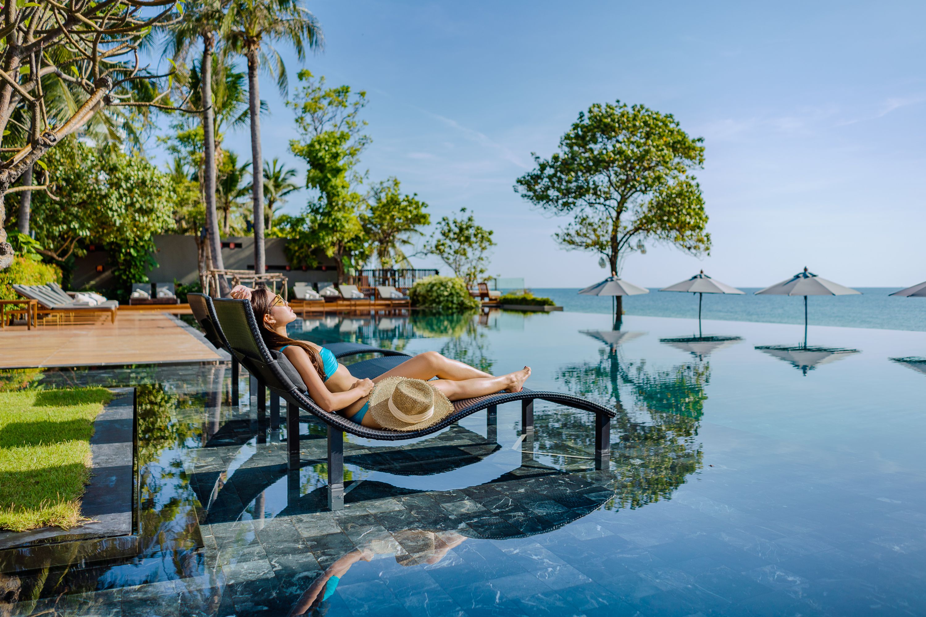 Woman relaxing by infinity pool at a tropical resort