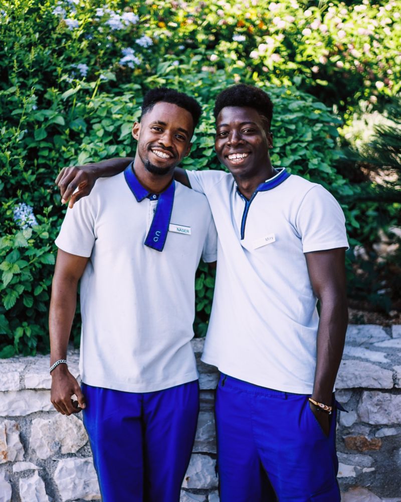 Two smiling Mövenpick hotel staff members in white and blue uniforms