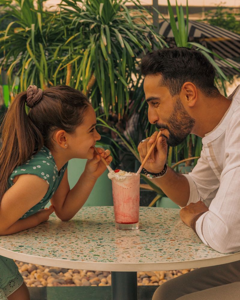 Father and daughter sharing a milkshake on the terrace at Mövenpick Hotel Dubai Downtown