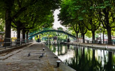 The quiet, tree-lined walkway and a cast-iron bridge at Canal Saint-Martin, Paris