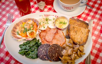 Breakfast-Teller in Terry's Cafe mit Black Pudding und geräuchertem Speck auf karierter Tischdecke
