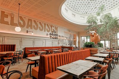 Restaurante con techos altos, cúpula, letras grandes y bancos y mobiliario naranja