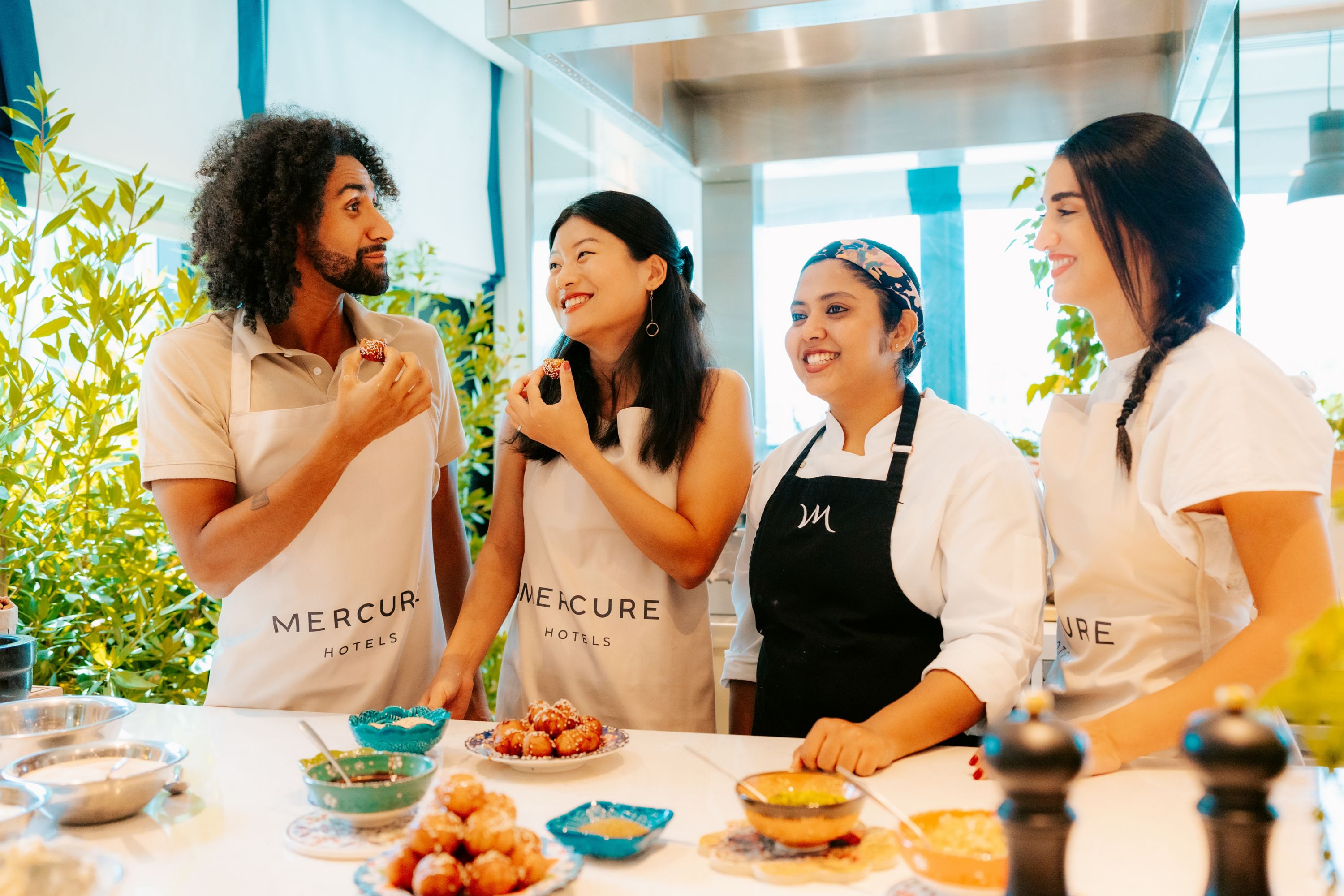 A group of friends with a chef eating and preparing food at the restaurant at Mercure Dubai Deira
