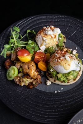 eggs benedict with roasted potato on a black plate