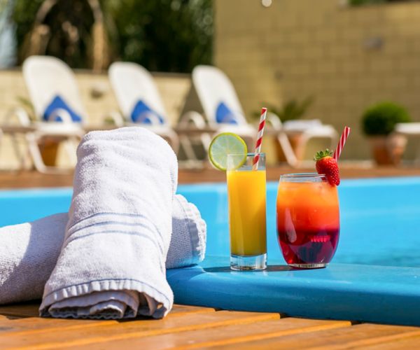 Piscina do hotel Novotel Porto Alegre Tres Figueiras, com toalha e sucos em foco na beira da piscina