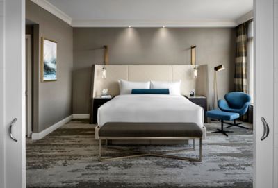 A hotel room with a king bed and chair