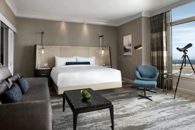 Chambre d’hôtel avec lit, table basse, fauteuil, canapé et télescope