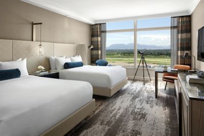 Hotel room with two beds, TV, desk, telescope, and chair 