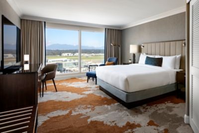 A hotel room with a king bed, desk, and chair