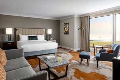 Une chambre d’hôtel avec un lit King size, un canapé, une table basse et un fauteuil