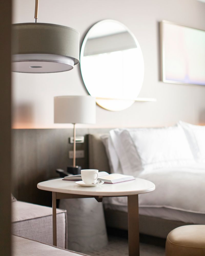 A hotel bed with a night stand and mirror on the wall