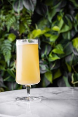 A cocktail on a marble table in front of greenery
