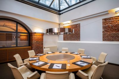 A round table set for a meeting in a sun-lit event space at Mövenpick Hamburg