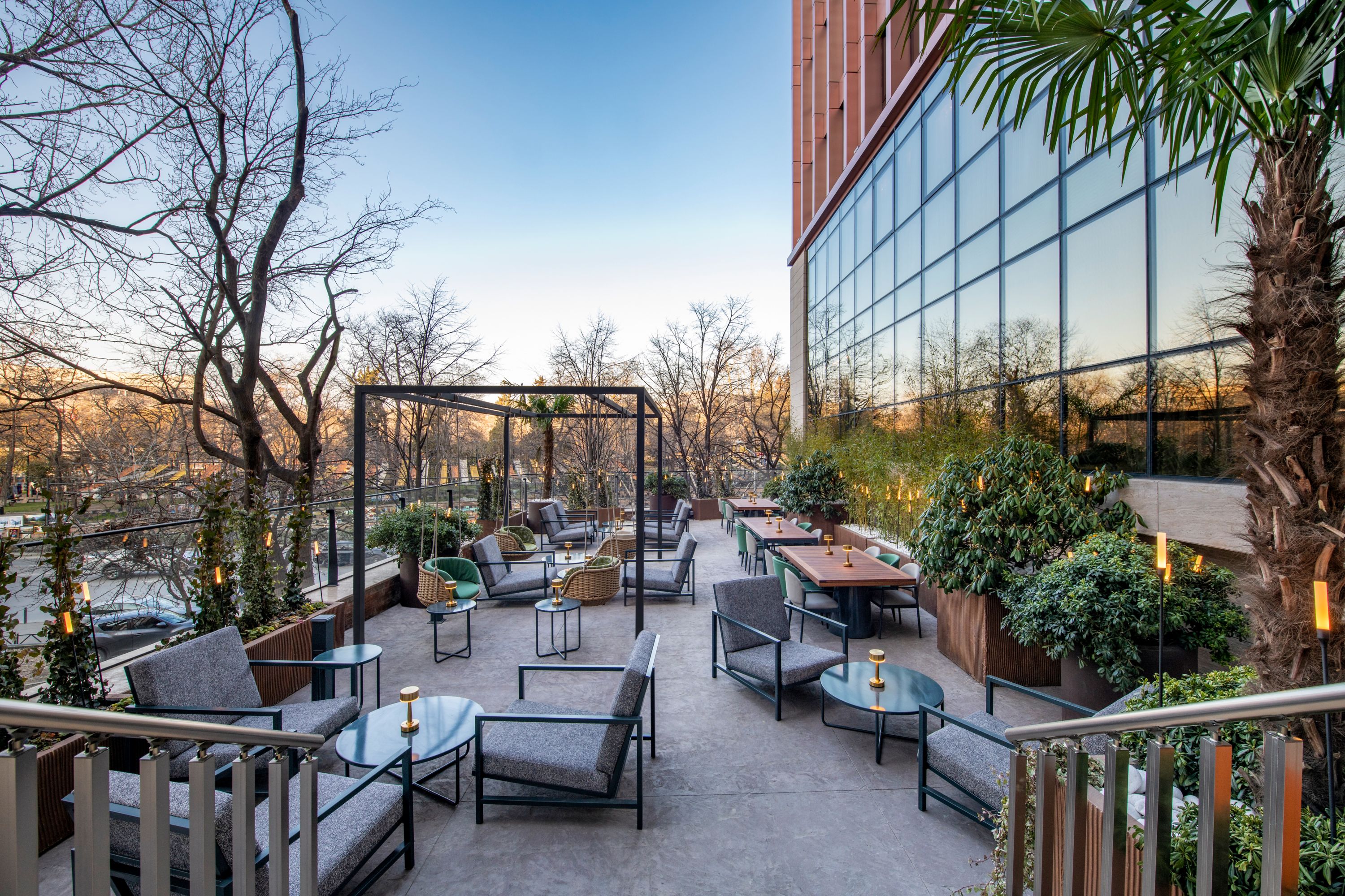 Terrasse végétalisée avec fauteuil et table au bar du Swissôtel Tbilisi