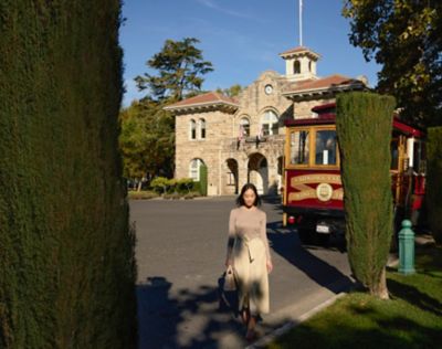 Woman walking in front of historic plaza building and Sonoma wine trolley in the background