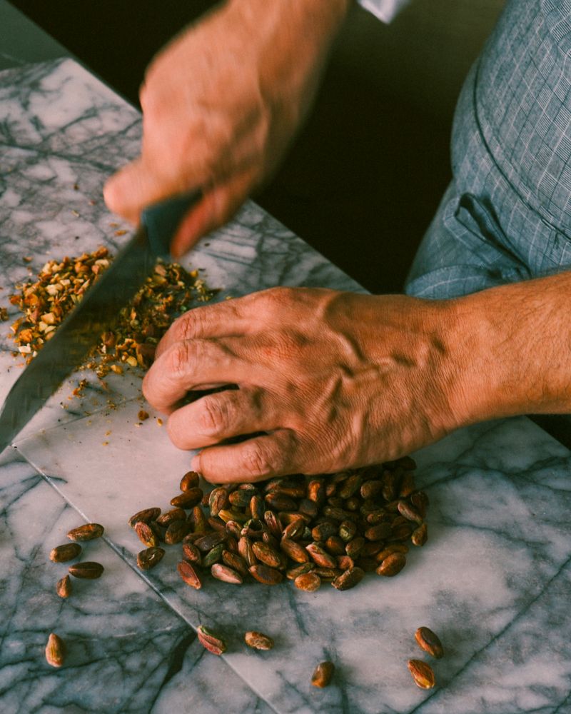 Mövenpick chef crushing fresh pistachios on a marble countertop