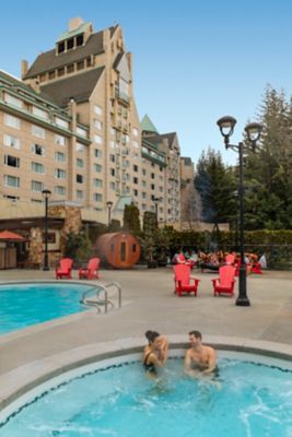 Two friends lounging by Fairmont Chateau Whistler pool