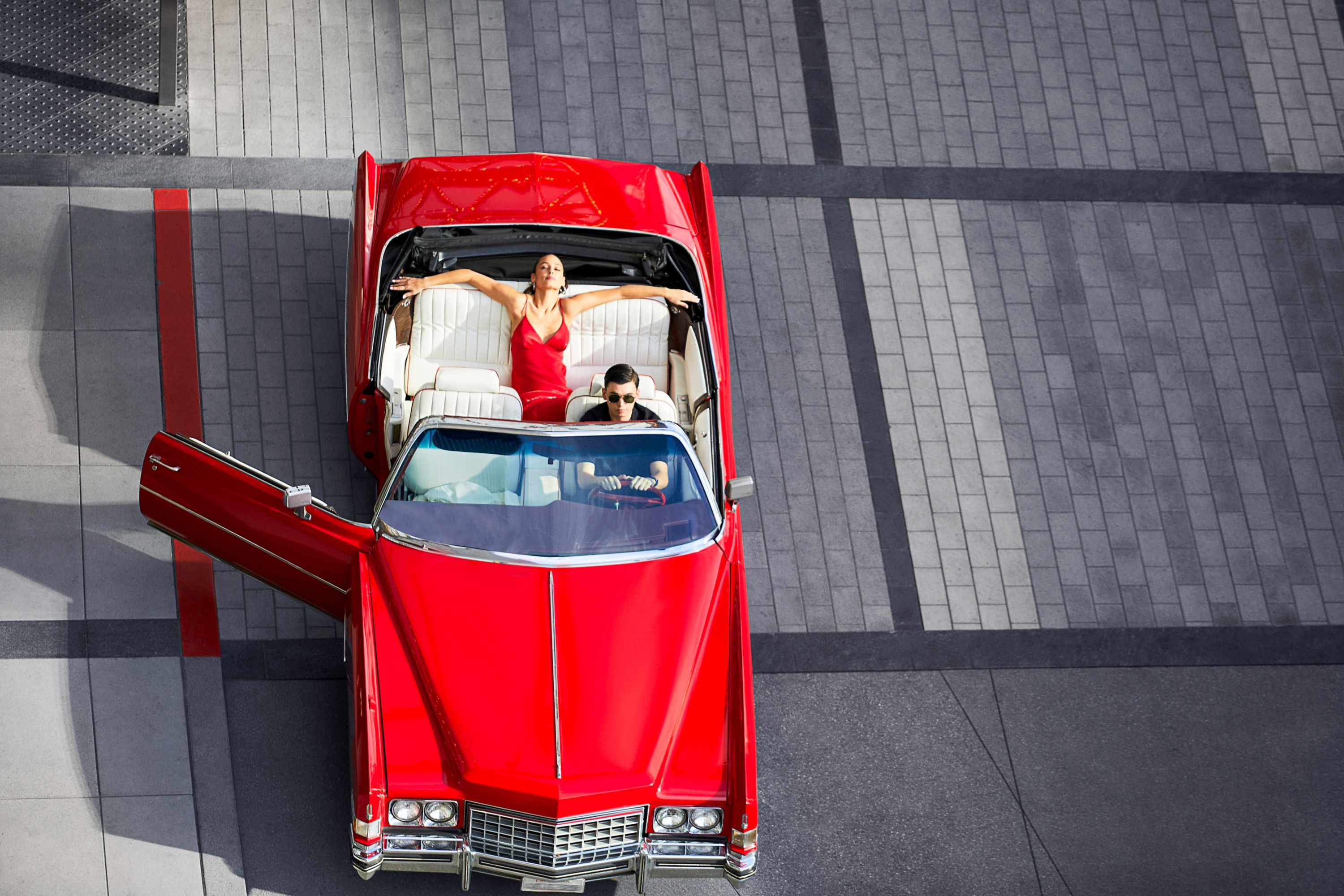 People sitting in a red convertible car