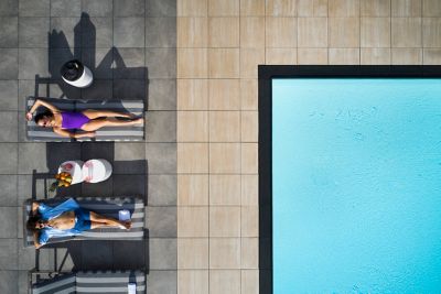Two people on lounge chairs next to a pool