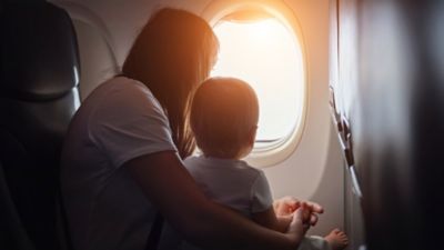 mãe com filho no avião olhando para a janela